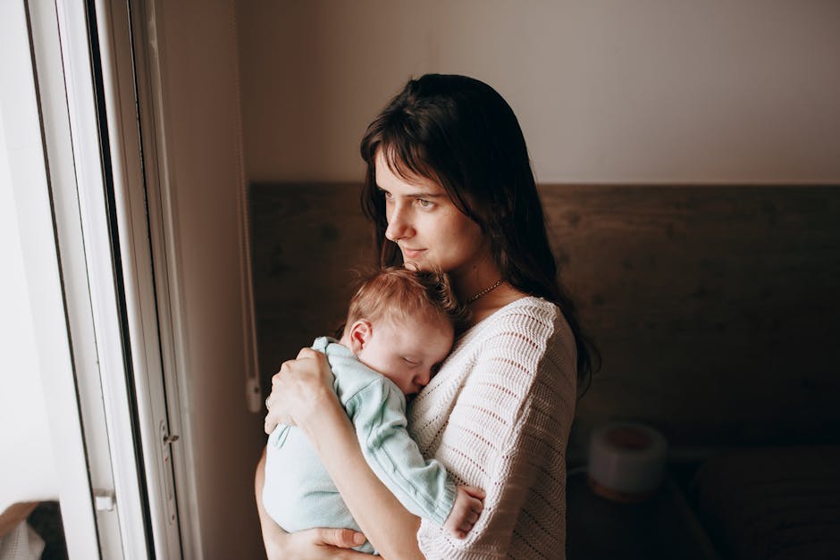 A serene image of a mother lovingly holding her sleeping baby indoors.