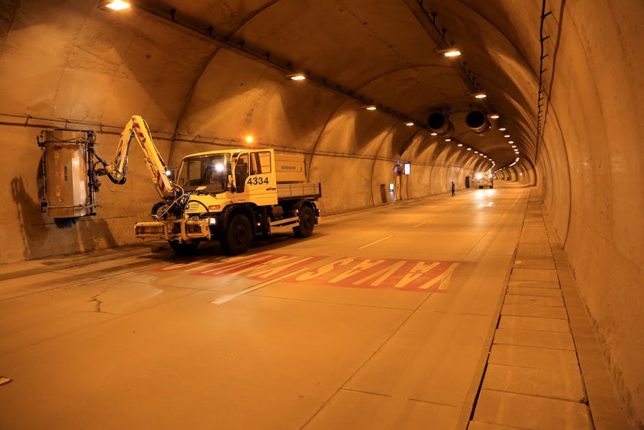 Illuminated tunnel with maintenance vehicle performing service tasks at night.