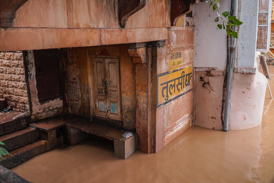 Image of a flooded building entrance in India, showing historical architecture and rising water levels.