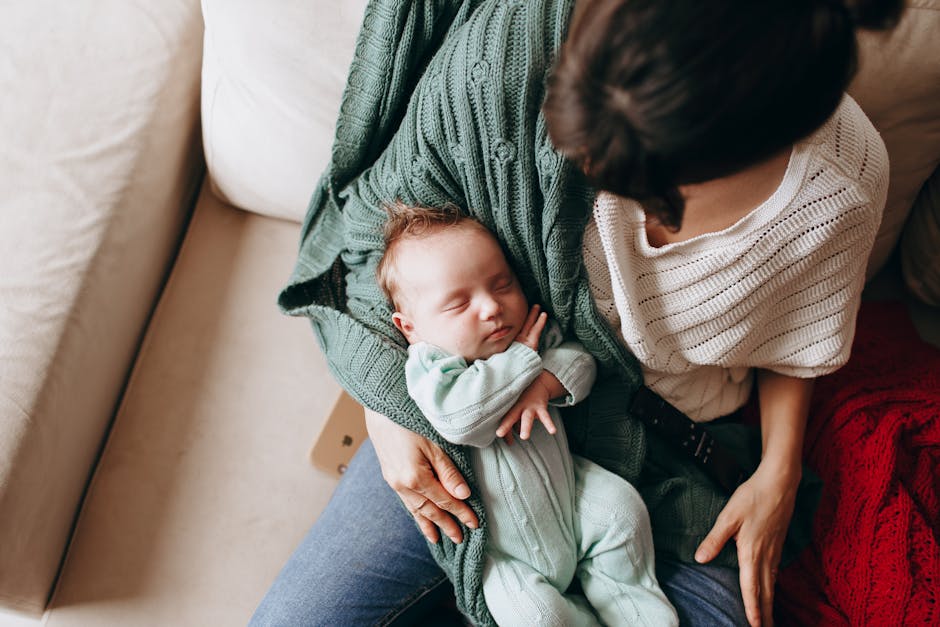 A serene moment of a mother holding her sleeping baby on a comfortable sofa indoors.
