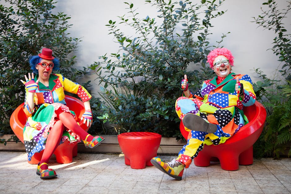 Vibrant clowns in colorful costumes sitting outside with red chairs, spreading joy and humor.