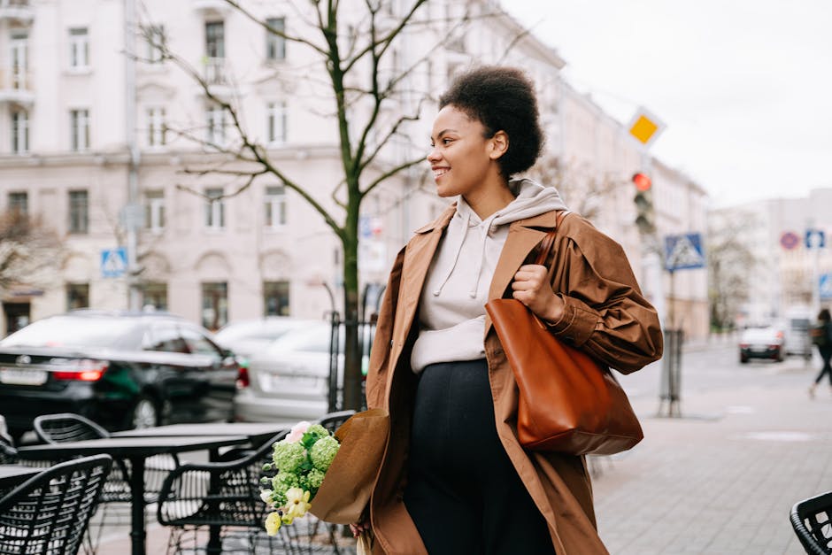 A pregnant woman walking with a bouquet in an urban area, smiling and enjoying the day.