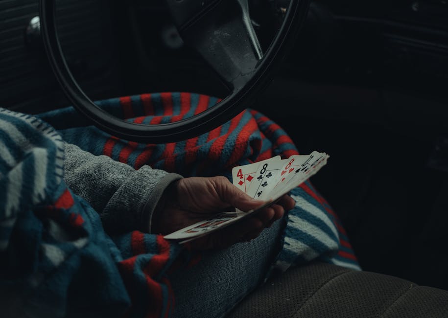 Close-up of a hand holding playing cards inside a vehicle, suggesting leisure travel.