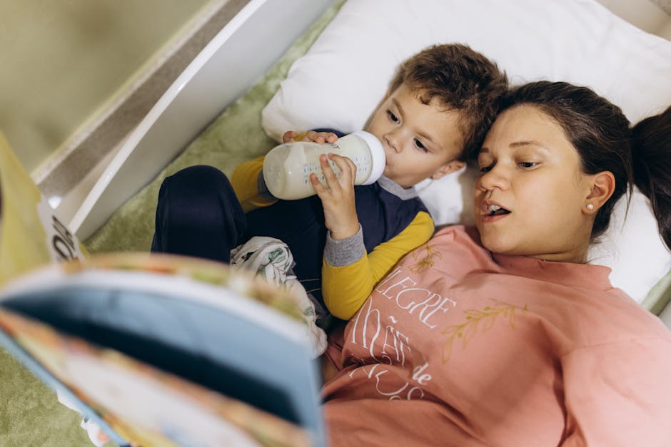 Mother and child lying in bed, bonding over a bedtime story and bottle feeding.