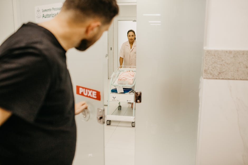 A man opens a door to see his newborn in a hospital room attended by a nurse.