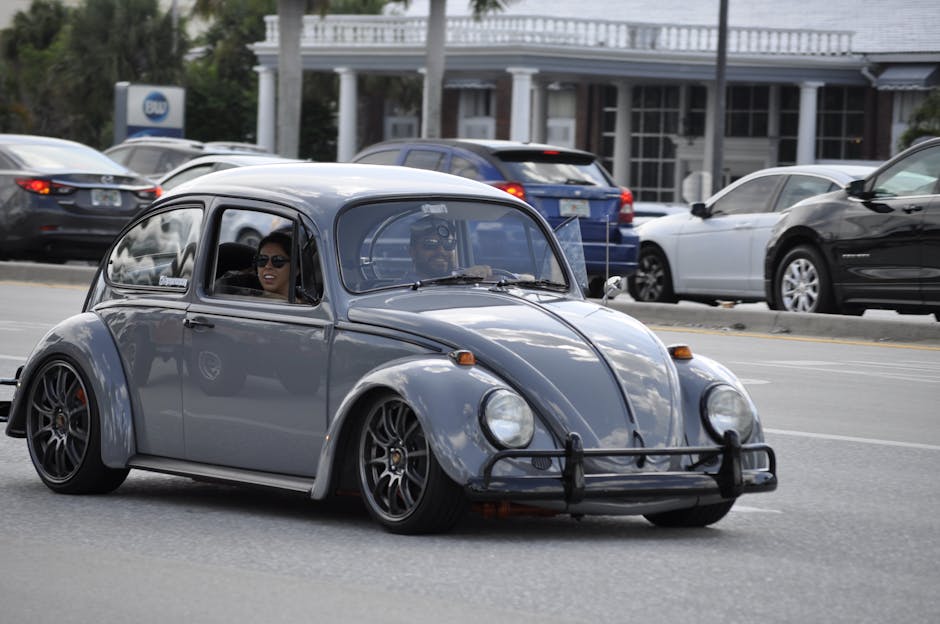 A vintage Volkswagen Beetle with passengers cruising down a city street, showcasing classic car design.