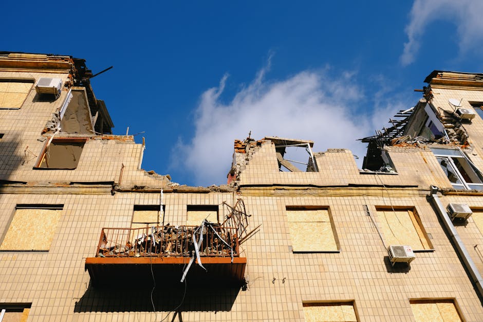 A destroyed residential building in Kharkiv, Ukraine under a blue sky.
