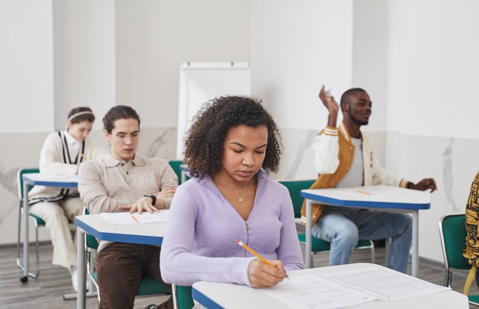 Group of diverse students focusing on exam in classroom setting.
