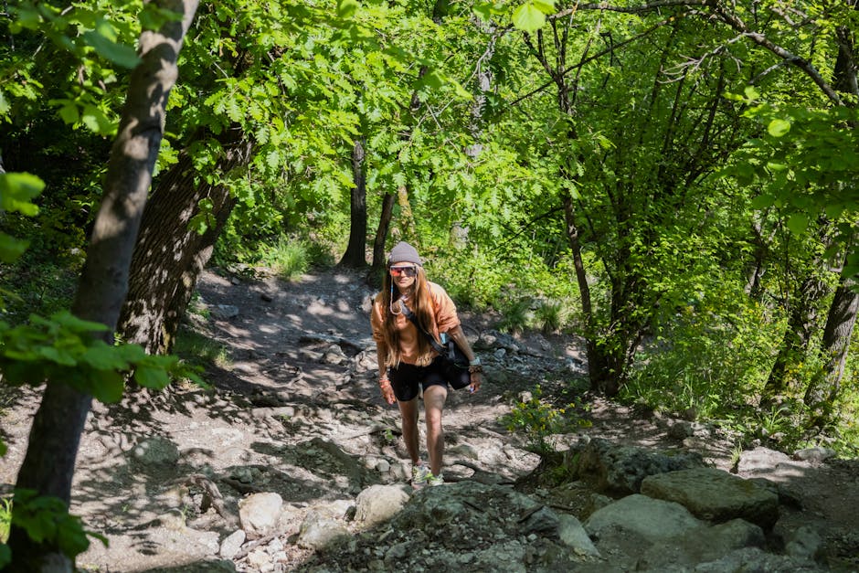 A young woman hiking through a vibrant green forest on a sunny day, capturing adventure and nature.
