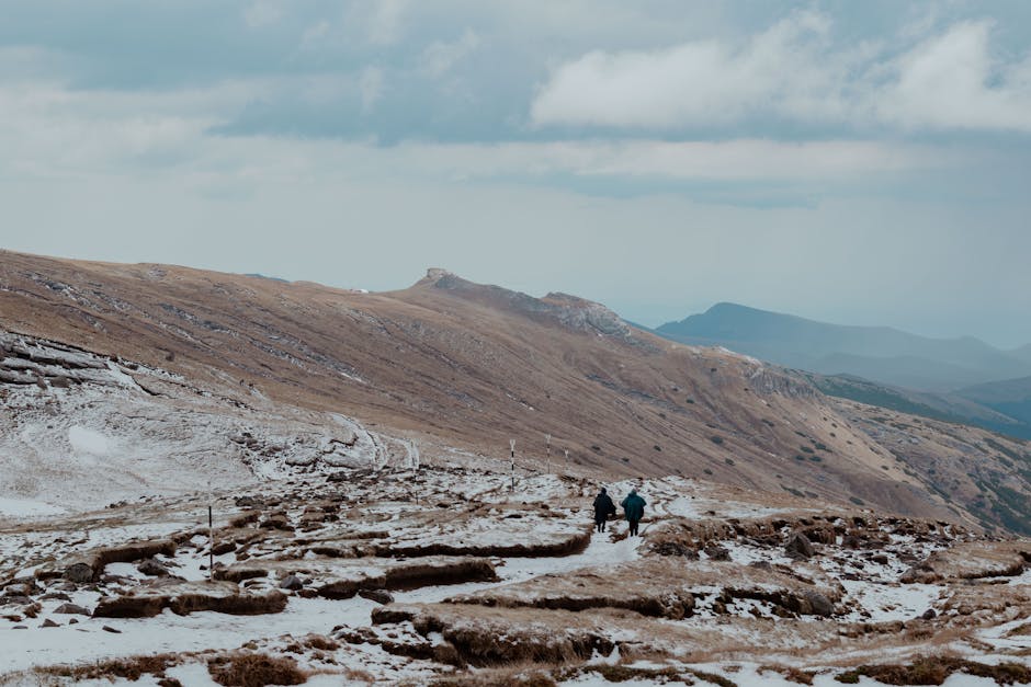 Hikers traverse a snowy trail in the scenic Bucegi Mountains, Romania.