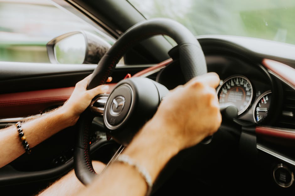 Close-up of hands gripping a car's steering wheel with visible dashboard gauges.