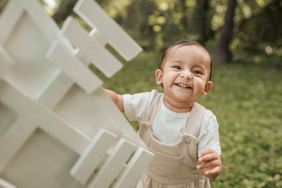 Cheerful toddler in overalls enjoying a playful summer day outdoors with a windmill.
