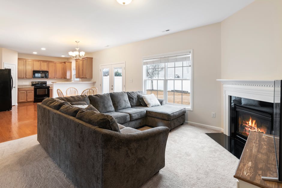 Modern living room with cozy sofa, fireplace, and open kitchen layout. Ideal for family gatherings.
