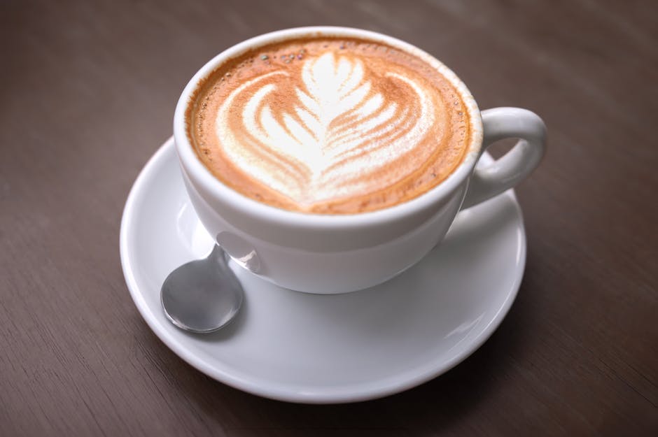 Close-up of a creamy latte with artistic leafy foam in a white cup on a wooden table, captured in Perú.