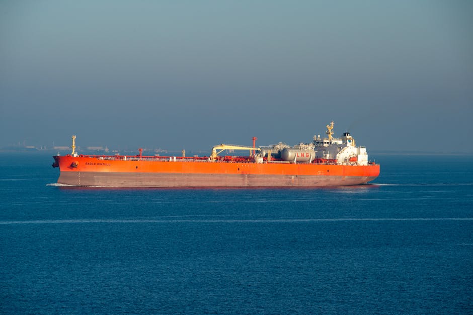 Bright orange LNG carrier ship cruising through calm sea waters on a clear day.