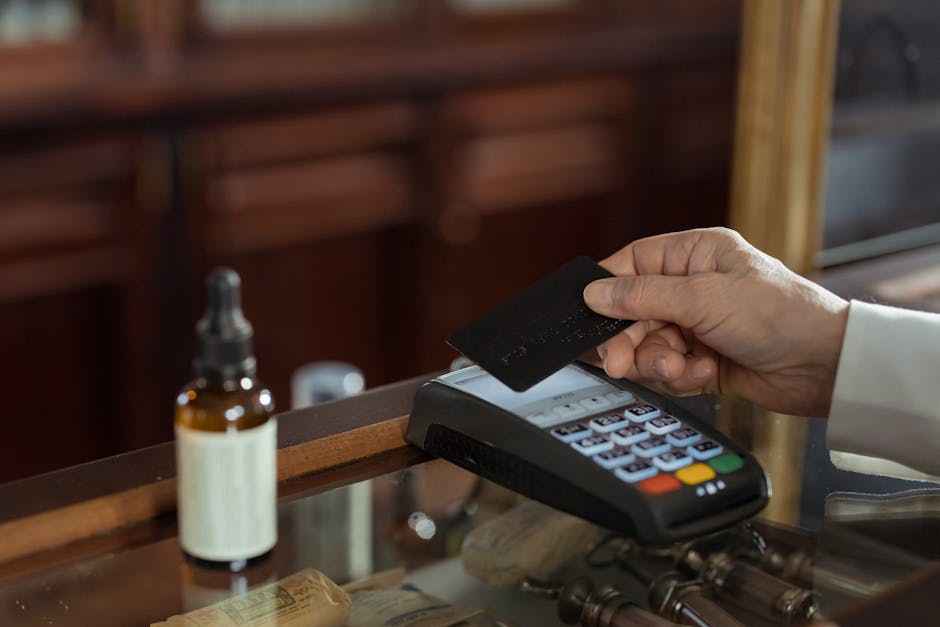 A close-up shot of a hand using a credit card with a swipe machine for payment.