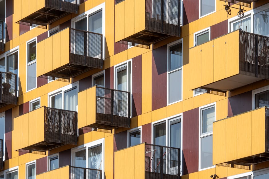 Close-up view of geometric modern residential building facade with balconies and contrasting colors.