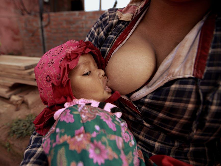 Close-up of a mother breastfeeding her baby outdoors, highlighting the bond and care.