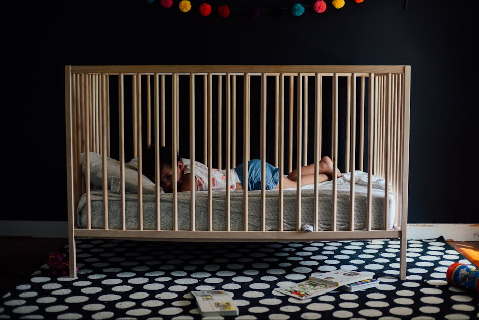 A baby peacefully sleeping in a crib inside a colorful and cozy nursery with soft lighting.
