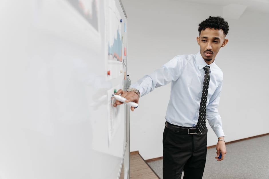 Business professional presenting graphs on a whiteboard in an office setting.