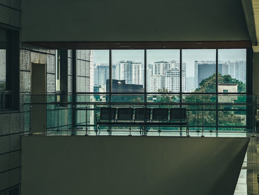 Spacious office interior with a large window overlooking a city skyline, offering a tranquil workspace.