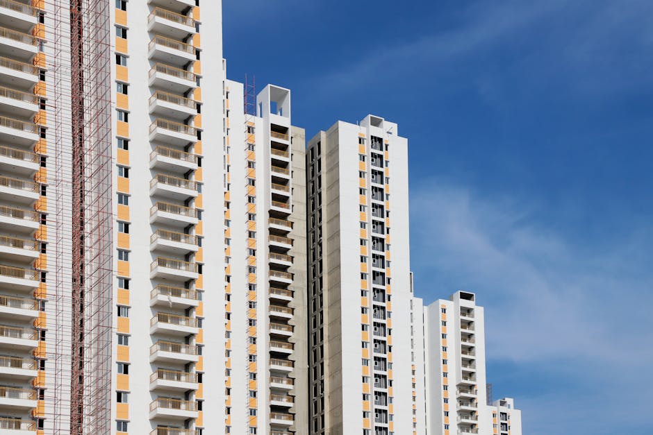 Modern high-rise residential buildings with white facades and blue sky backdrop showcasing urban architecture.