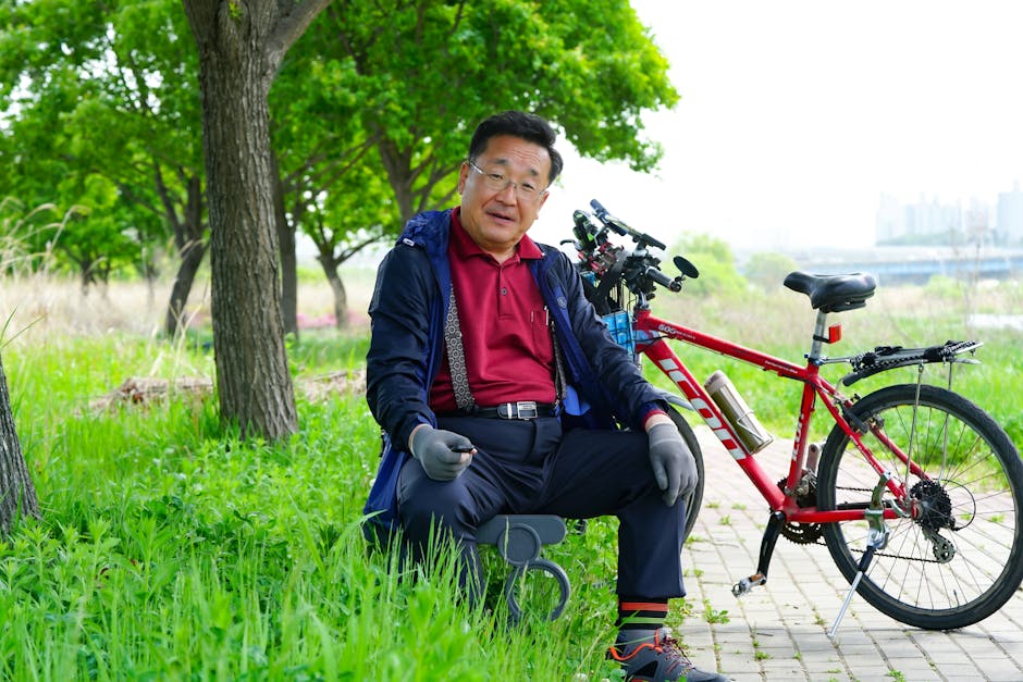 Mature Asian man enjoying leisure time outdoors with his bicycle on a sunny day.