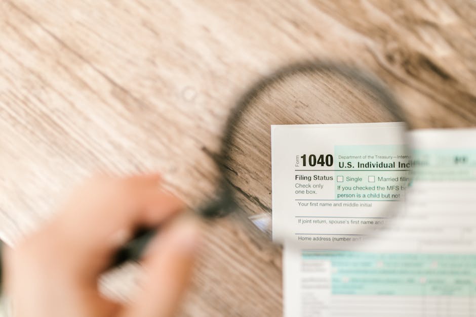 Close-up image of IRS Form 1040 under a magnifying glass on a wooden surface.