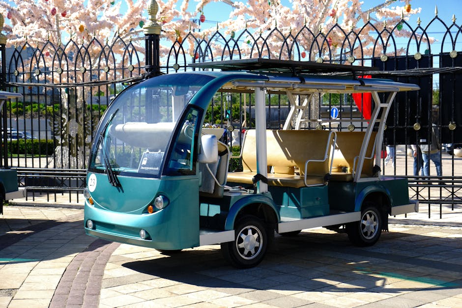 Modern electric shuttle parked in a scenic urban park setting under sunny skies.