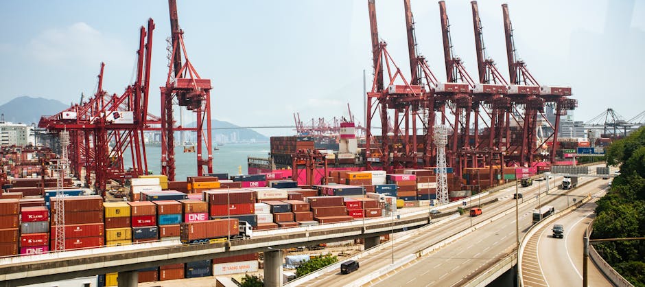 A vibrant view of Hong Kong's bustling shipping port with red cranes and stacked containers.
