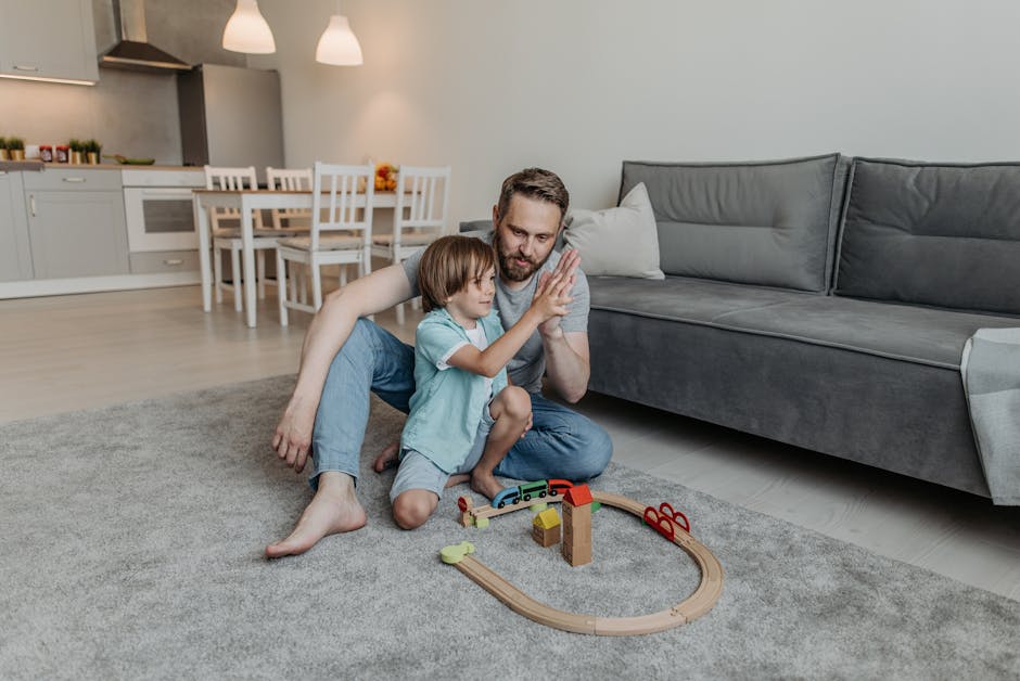 Father and son enjoying playtime indoors, building a toy train track together.