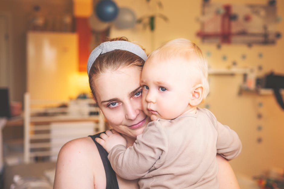 A mother lovingly holds her baby in a cozy indoor environment, showing bond and warmth.