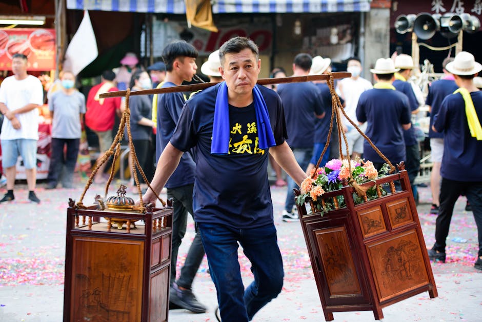 Man carrying traditional wooden decorations during a vibrant festival market.