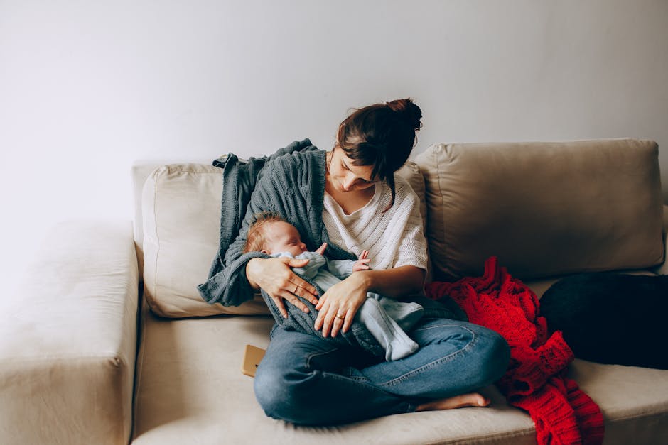 Tender moment of a mother holding her newborn baby on a cozy sofa, creating a heartfelt family scene.