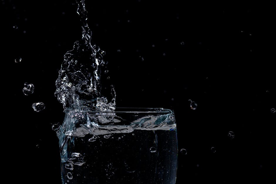 Close-up of water splashing in a glass against a black background.