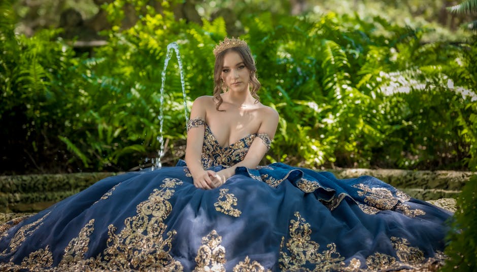 A young woman in a royal blue gown sits gracefully in a lush green garden.