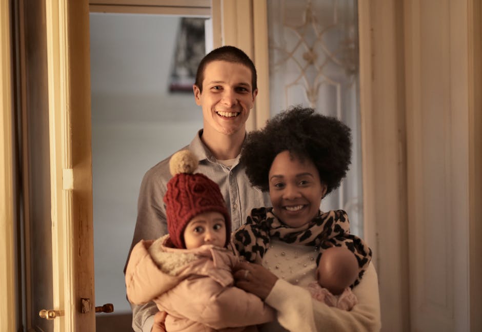 Smiling parents holding a baby in winter attire, showcasing family love indoors.
