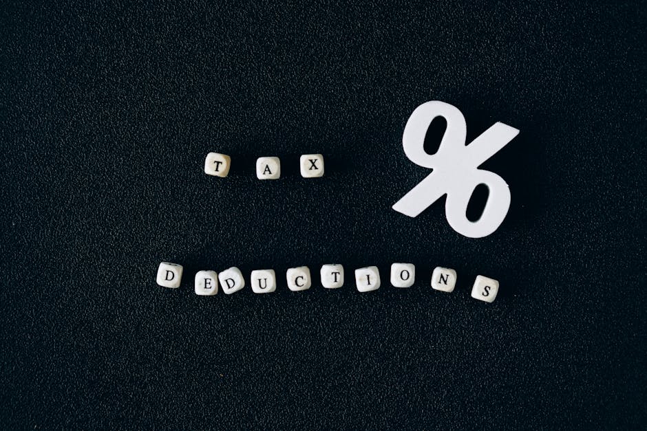 Conceptual image of tax deductions with alphabet blocks and percent symbol on black surface.