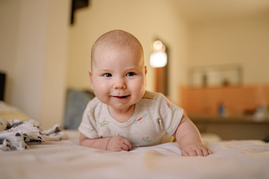 Cute baby in a onesie smiling while lying on a bed indoors.
