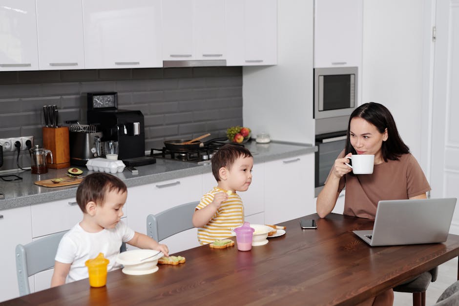 Mother and two sons enjoying breakfast while using a laptop in a contemporary kitchen.