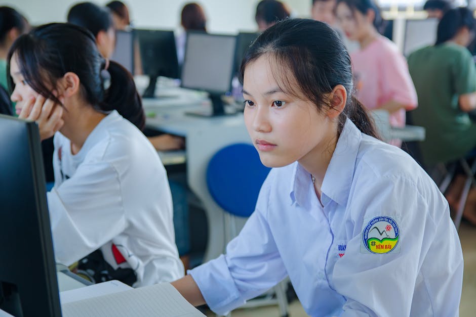 Young students in uniform studying at computers for teamwork and education.