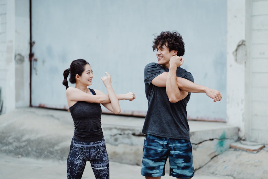 Man and woman stretching outdoors in sports clothing, smiling and exercising together.