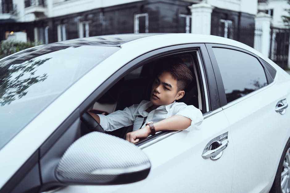 Self assured young ethnic male in white shirt driving modern car on city street in daytime