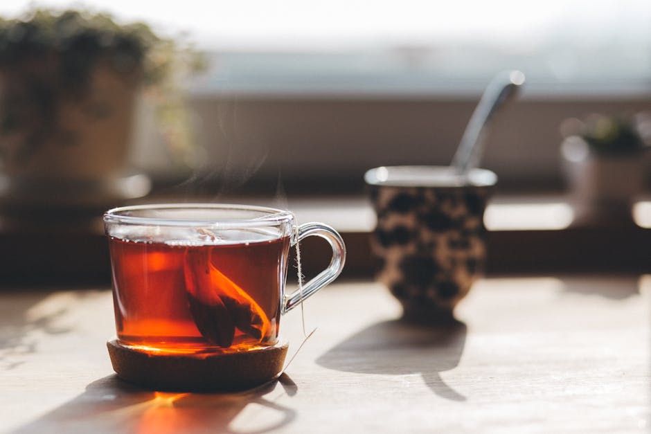 A steaming cup of tea in glass cup with sunlight and cozy indoor ambiance.