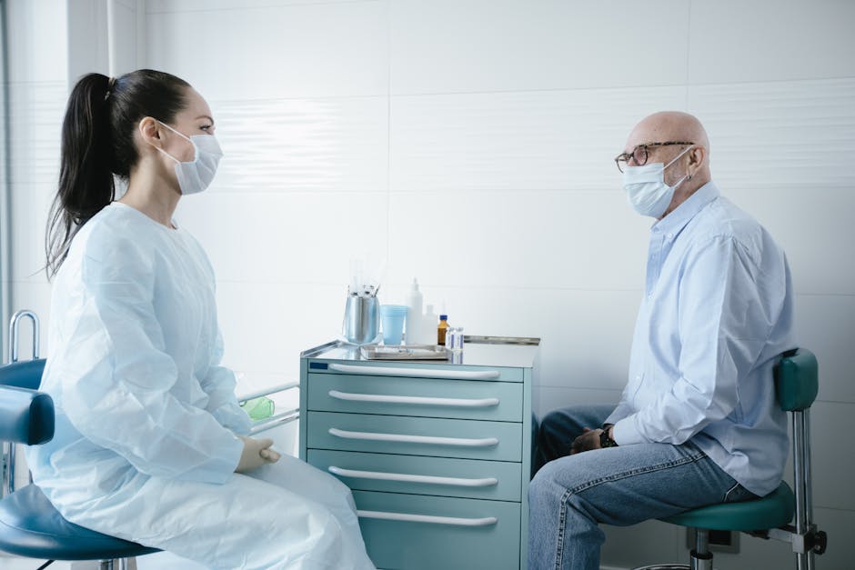 Medical professional consults a senior patient, both wearing masks in a clinic setting.