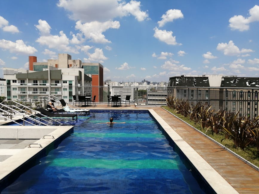 A serene rooftop pool with a view of São Paulo's skyline under a clear blue sky, offering a relaxing urban escape.