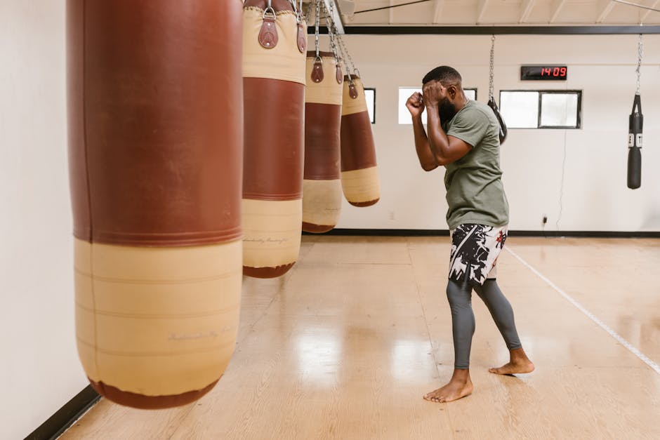 Black male athlete training with punching bags in the gym. Focus on martial arts techniques indoors.