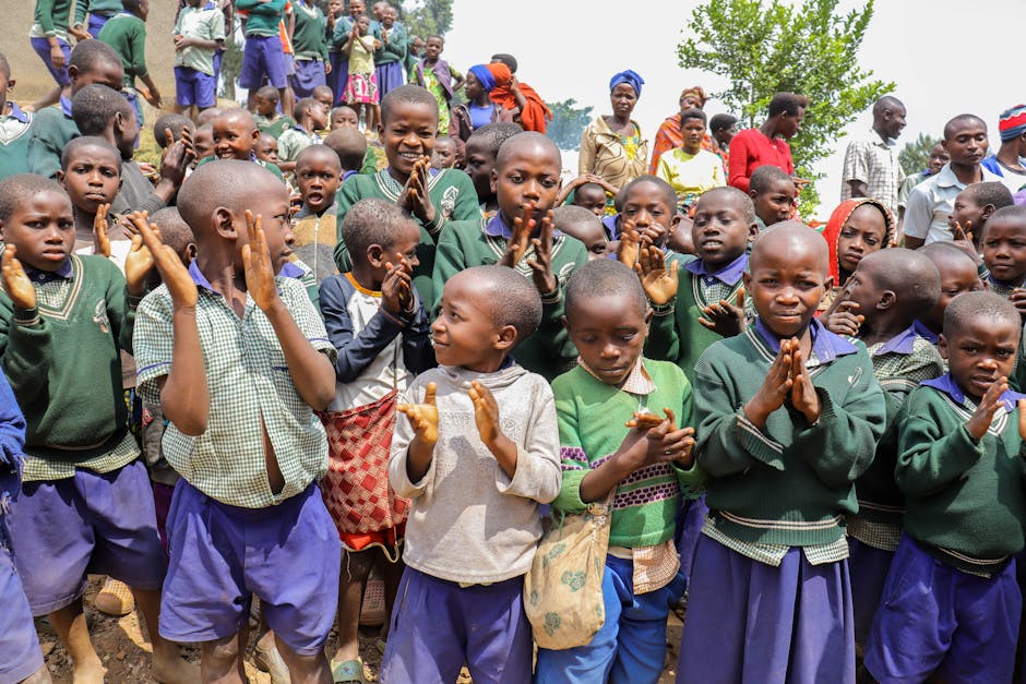 Joyful group of African children clapping and smiling in an outdoor rural setting.