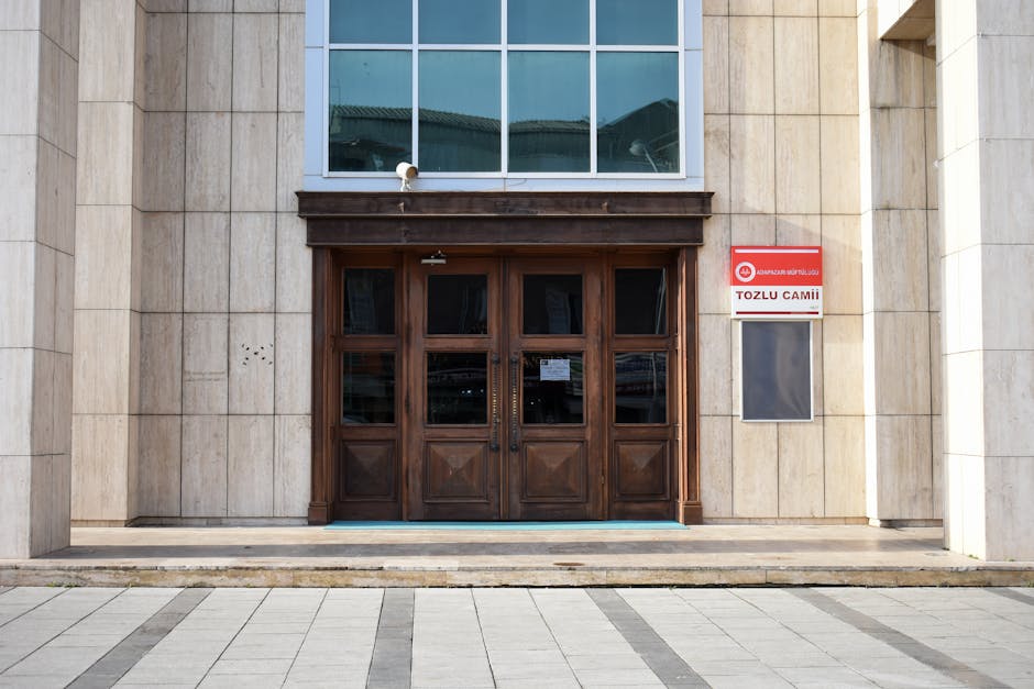 Wooden doors leading into a modern mosque facade, featuring traditional elements and contemporary design.