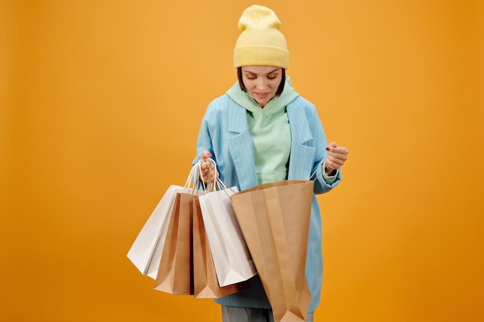 Stylish woman in colorful outfit holding multiple shopping bags against a vibrant yellow background.